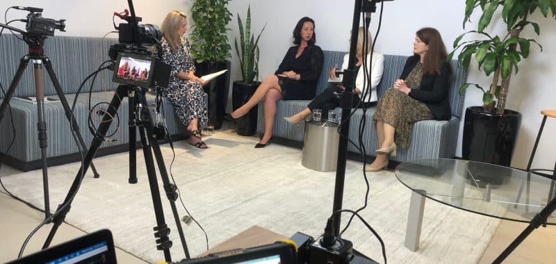 Three women in corporate office being filmed